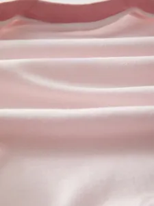 Close-up of soft pink combed cotton fabric showing breathable texture for baby rompers