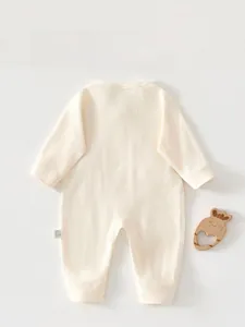 Detail showing soft cotton knit texture and washing label on newborn jumpsuit