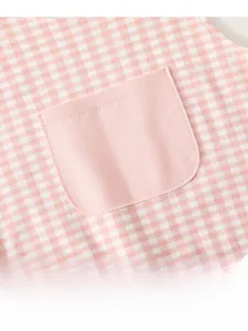 Close-up of pink gingham baby bib fabric featuring a practical solid color front pocket