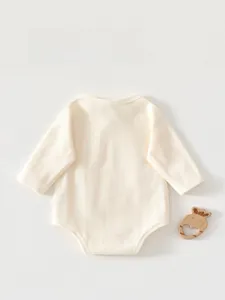 Detail of baby long sleeve romper featuring soft ribbed cotton fabric and snap button closure
