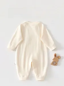 Dettaglio del retro di una tutina color crema per neonati con trama a nido d'ape morbida
