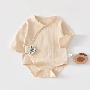 Detail of baby cotton bodysuit featuring vertical ribbed texture and bird embroidery