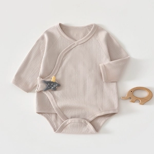 Close-up of baby romper with ribbed texture and star patch on soft beige cotton fabric