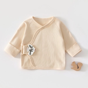 Détail d'un haut kimono pour bébé en coton bio avec texture côtelée et broderie de poisson
