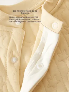 Macro detail of food-grade POM resin snap buttons on light yellow star-quilted baby clothes