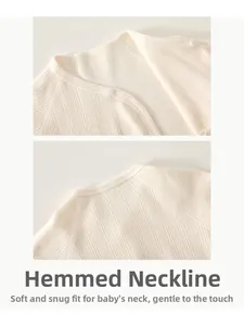 Close-up of the ribbed cotton edge and button detail on a soft beige newborn romper