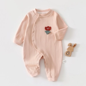 Dettaglio tutina in cotone neonato con tessuto a coste rosa e ricamo a tulipano