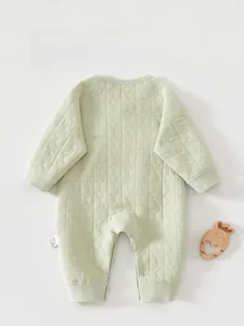 Detail of light green quilted baby romper featuring textured star and moon embossing