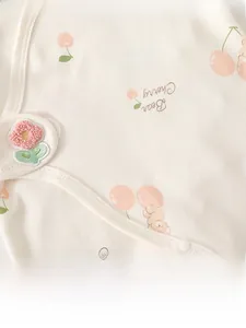 Detailed close-up of baby romper fabric with cherry bear prints and flower embroidery