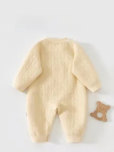 Detail view of baby romper featuring quilted moon and star patterns on beige cotton fabric