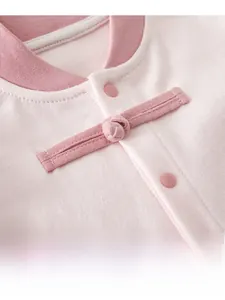 Detail of pink cotton baby jumpsuit featuring traditional Chinese handmade knot and snap button
