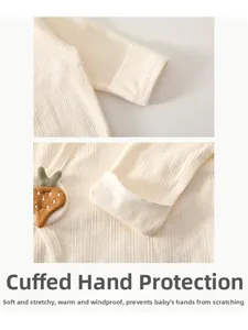 Détail de la manche en coton pour bébé avec revers anti-griffures et broderie carotte