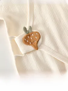 Detail of soft ribbed cotton newborn romper featuring a cute orange carrot patch design