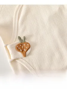 Detail of baby cotton bodysuit with cream jacquard fabric and carrot embroidery