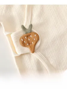 Détail d'un haut kimono bébé en coton crème avec écusson carotte et texture jacquard