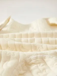 Close-up of baby romper fabric with embossed moon and stars on quilted cotton