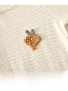 Dettaglio del tessuto della tutina neonato con trama a maglia e ricamo a carota