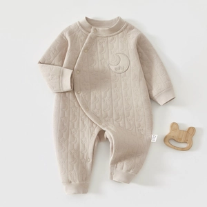 Detail of beige quilted baby romper featuring celestial textures and star patterns