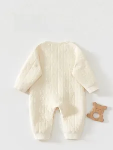 Detail of quilted newborn onesie featuring soft moon and star texture on beige cotton