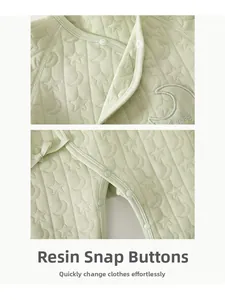 Detail of resin snap buttons and star-moon quilted texture on mint baby romper