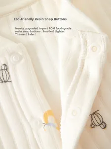 Detail of eco-friendly POM resin snaps on a soft cream cotton baby ribbed romper