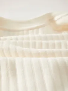 Close-up of warm beige ribbed knit fabric showing soft cotton texture and breathability