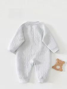 Détails de la grenouillère bébé avec motifs d'étoiles et de lune en relief sur tissu bleu