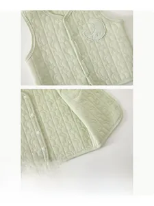 Close-up of resin buttons and baby embroidery on quilted light green infant vest