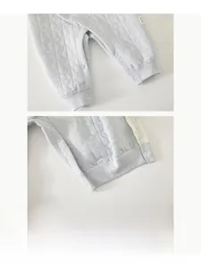 Détail des boutons-pression à l'entrejambe et de la texture matelassée du barboteuse bébé