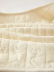 Detail view of the quilted baby vest fabric with soft star and moon embossed textures