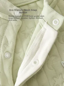 Detail of eco-friendly resin snap buttons on light green quilted cotton baby romper