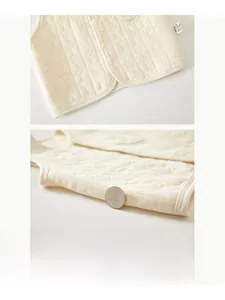 Close-up of quilted baby cotton vest with moon and star patterns and snap button