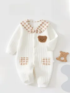 Detail of baby romper featuring rib-knit cotton texture, brown plaid collar and bear patch