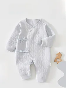 Détail d'un body matelassé pour bébé avec texture étoiles et lunes et nœuds latéraux