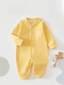Macro detail of soft light yellow newborn romper with button closure and bear print
