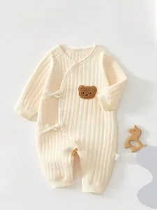 Vue détaillée d'une grenouillère bébé côtelée avec écusson ours et nœuds latéraux