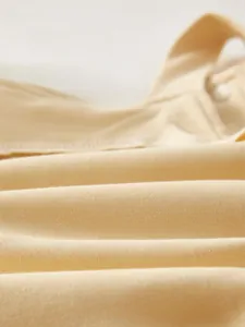 Close-up of soft beige combed cotton fabric with fine stitching and snap button detail