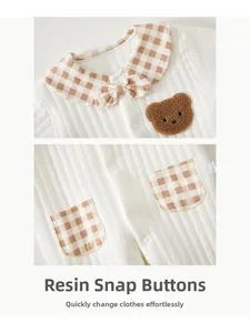 Detail of baby cotton romper featuring resin snap buttons and classic brown plaid collar