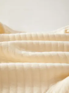 Gros plan sur le tricot de coton beige doux avec une texture fine de rayures verticales