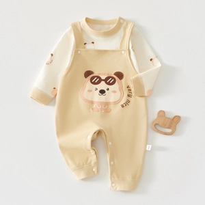 Detail of baby cotton set with bear embroidery and side size tag on beige fabric