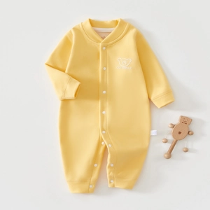 Detail of yellow infant romper featuring a cute bear logo and convenient snap buttons