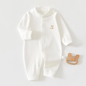Dettaglio body neonato in cotone bianco con trama a costine e ricamo a orsetto