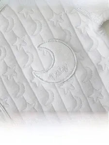 Détail de la grenouillère bébé avec motifs jacquard étoiles et écusson lune brodé