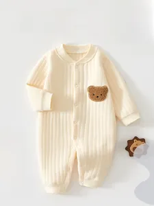 Détail d'une grenouillère bébé beige montrant le tissu côtelé et le patch d'ours en peluche