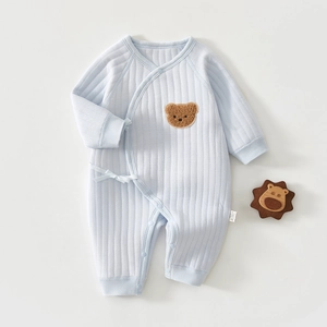 Détail du body bébé matelassé bleu clair avec patch ours et fermeture ruban