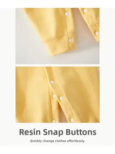 Detail of yellow newborn jumpsuit featuring convenient white resin snap buttons for easy dressing