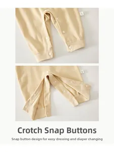 Detailed close-up of snap fastener crotch design on cream soft cotton baby romper