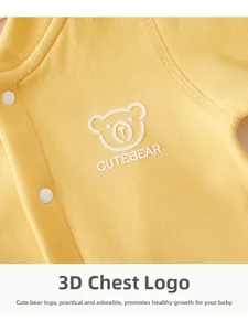 Detail of baby romper featuring a 3D bear patch and CUTEBEAR text on soft yellow cotton