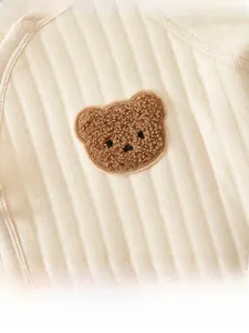 Détail de la grenouillère pour nouveau-né avec texture côtelée et broderie ourson
