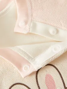 Detail of pink and beige baby romper with shoulder snaps and soft herringbone texture